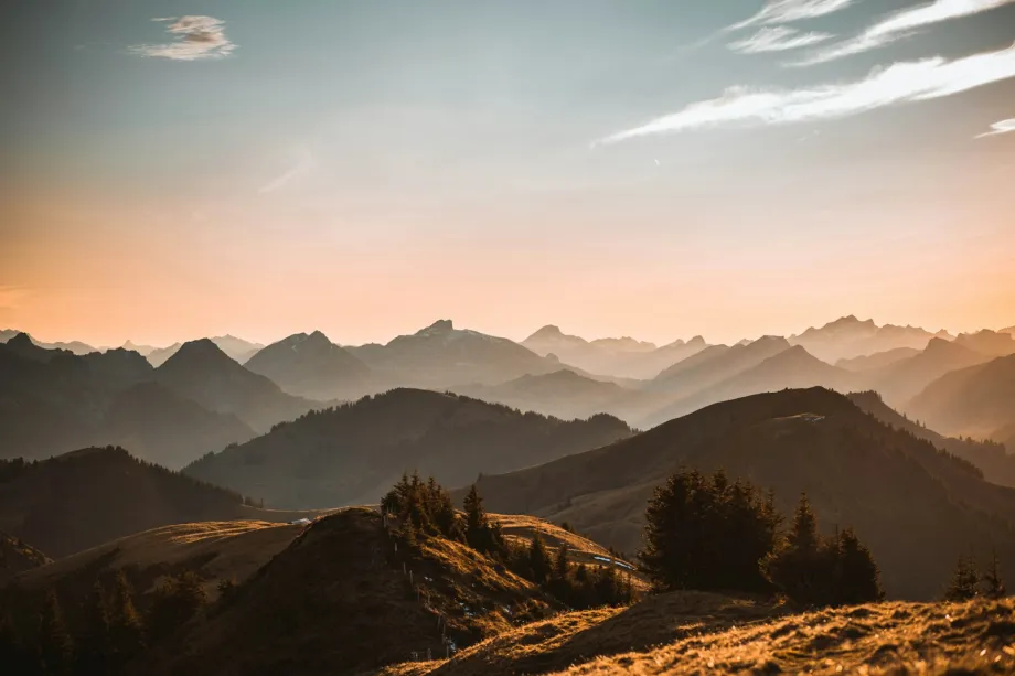 Layered mountain ridges under a warm orange sky with long shadows