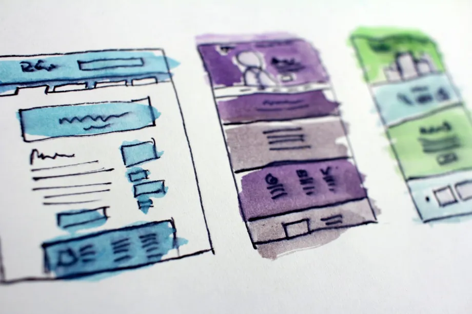 Watercolor wireframe sketches of website page layouts on white paper