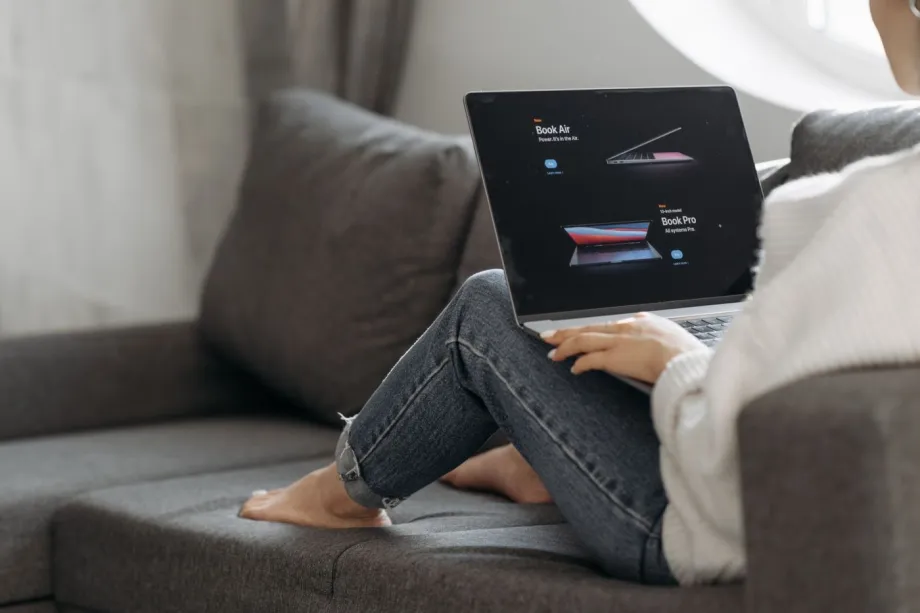 A person sitting at a desk with a laptop, selecting a blog template from a website layout preview.